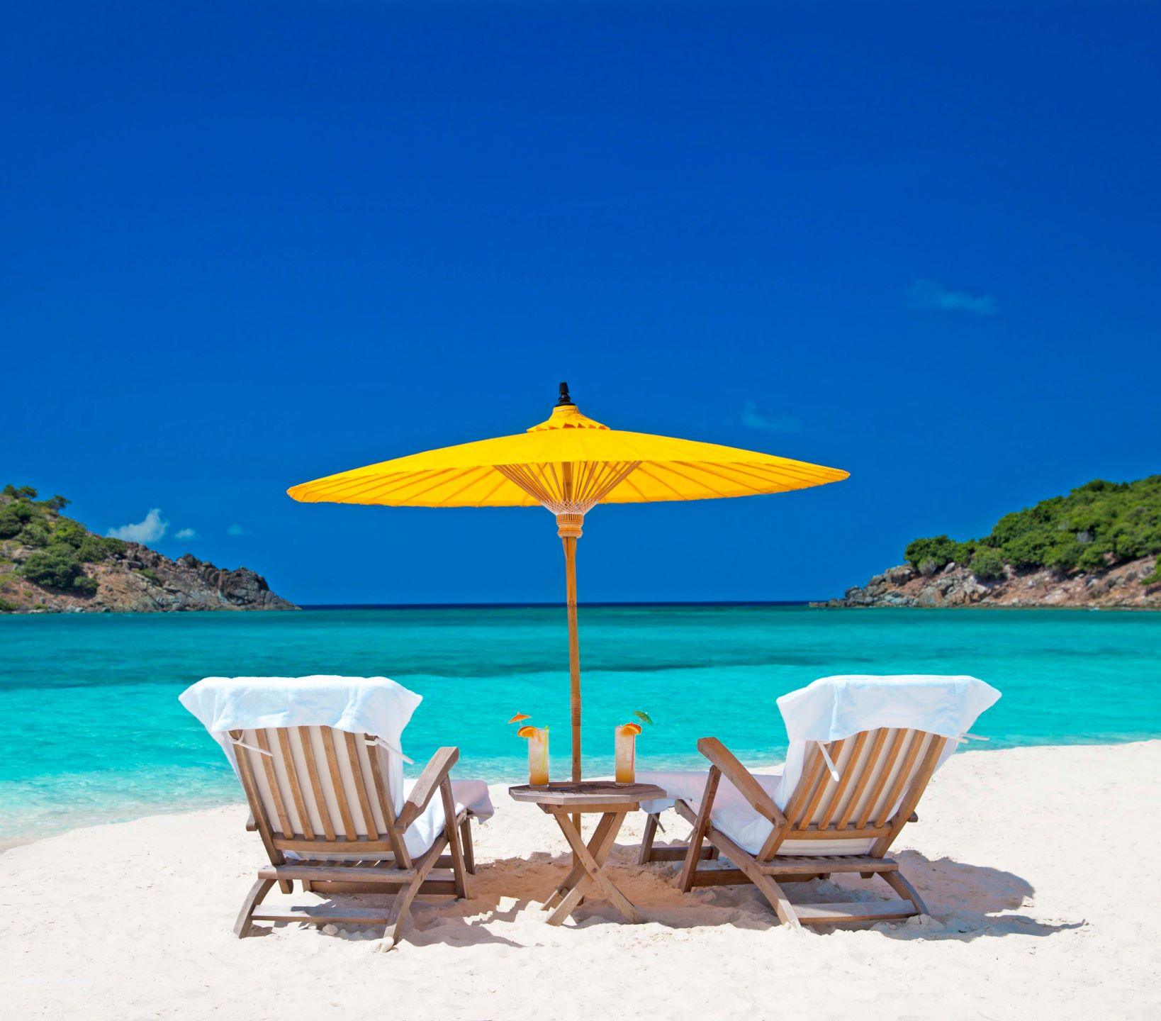 Two chairs and a yellow umbrella on a beautiful, vibrant beach