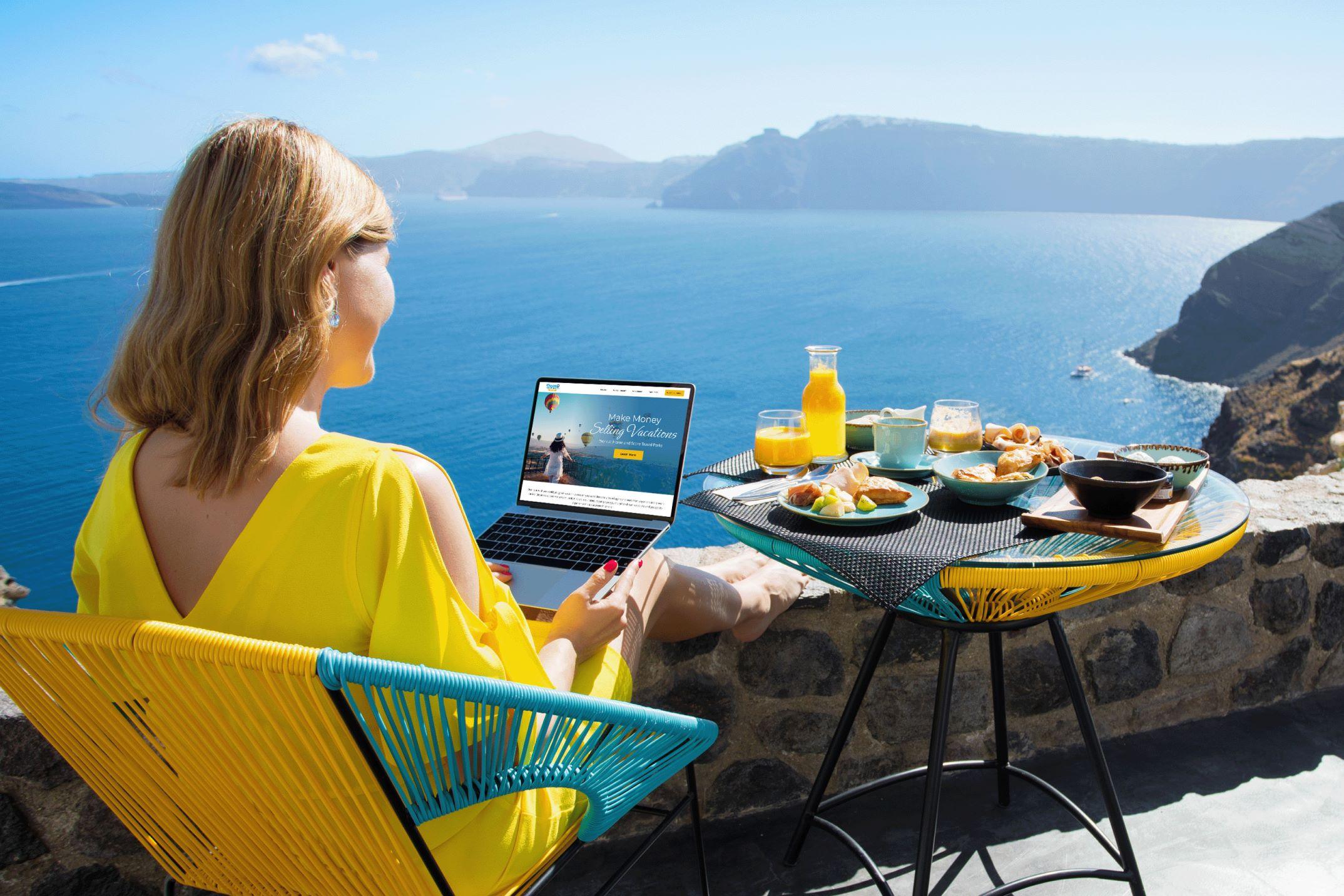 A woman in a bright yellow dress working at her laptop in a coastal villa