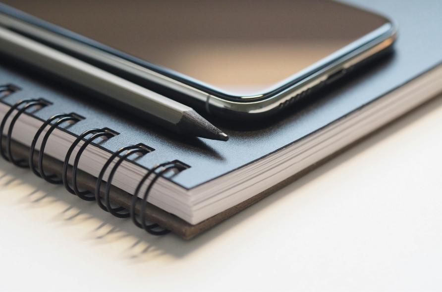 A phone and pen resting atop a notepad