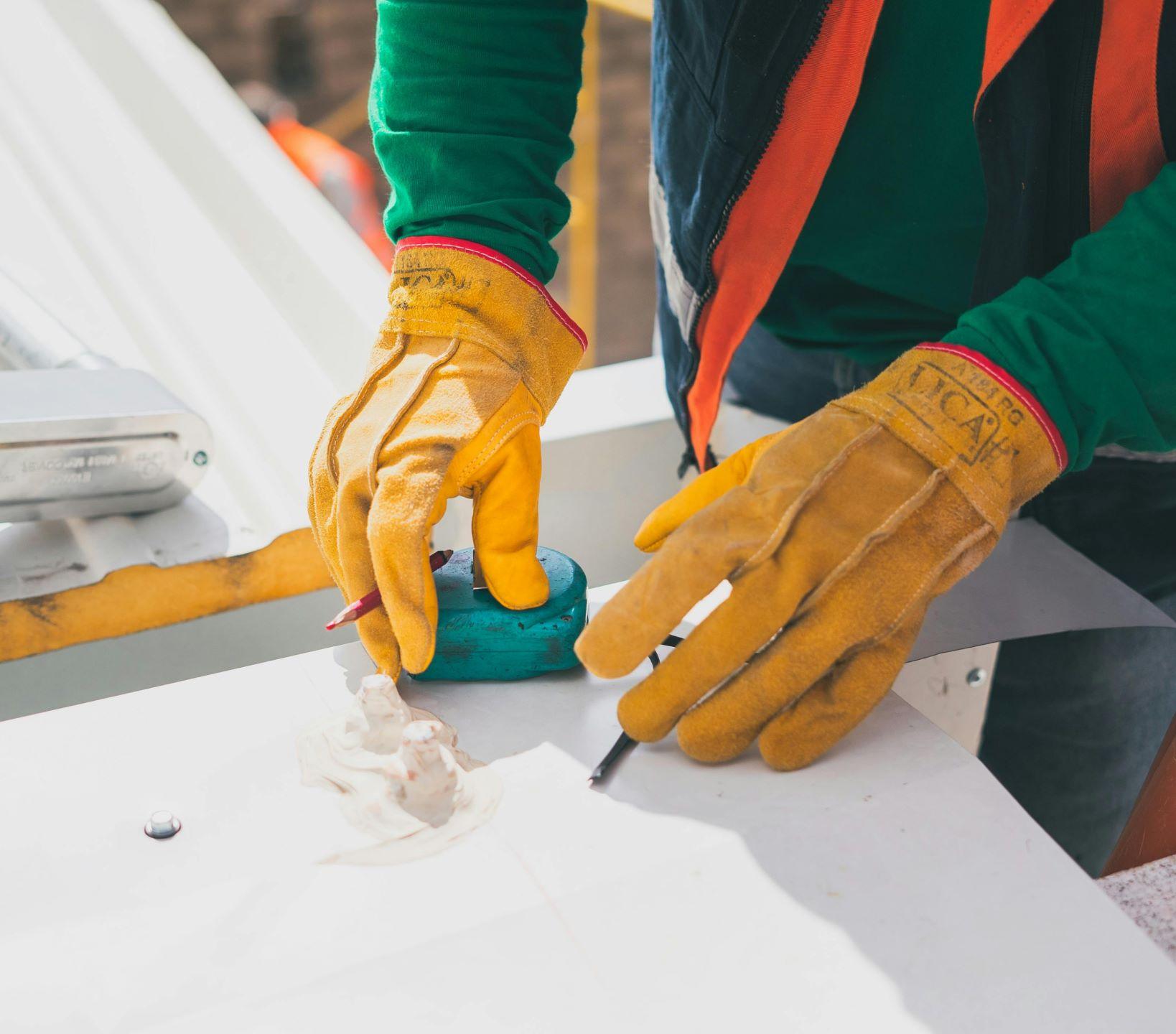 A contractor wearing thick yellow protective gloves