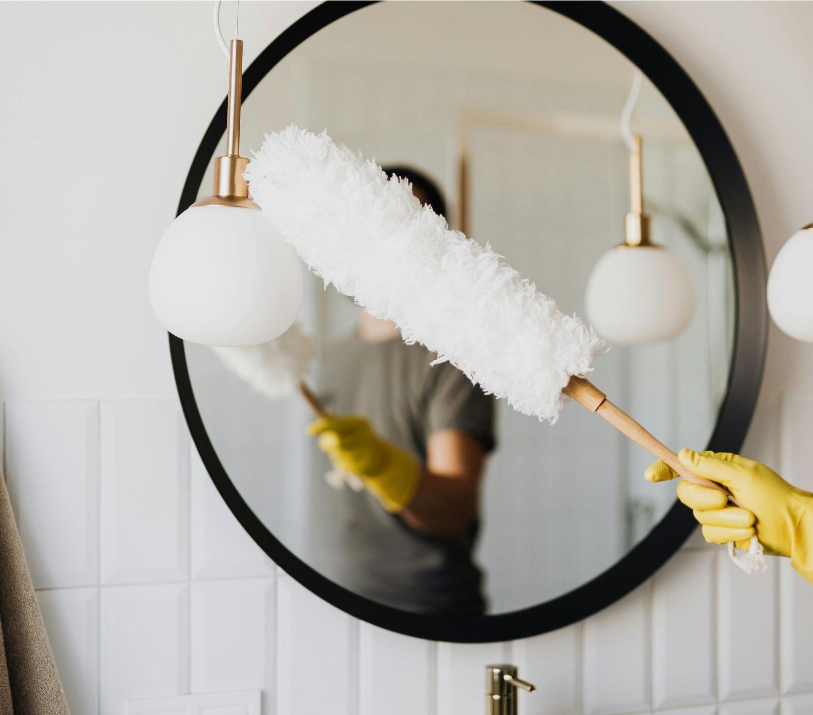 A PuroClean employee dusting a mirror